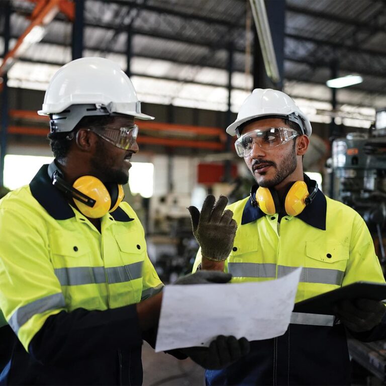 Image shows 2 workers in a factory wearing branded workwear provided by BrandXellence - Workwear_PPE_BrandXellence_Storefront